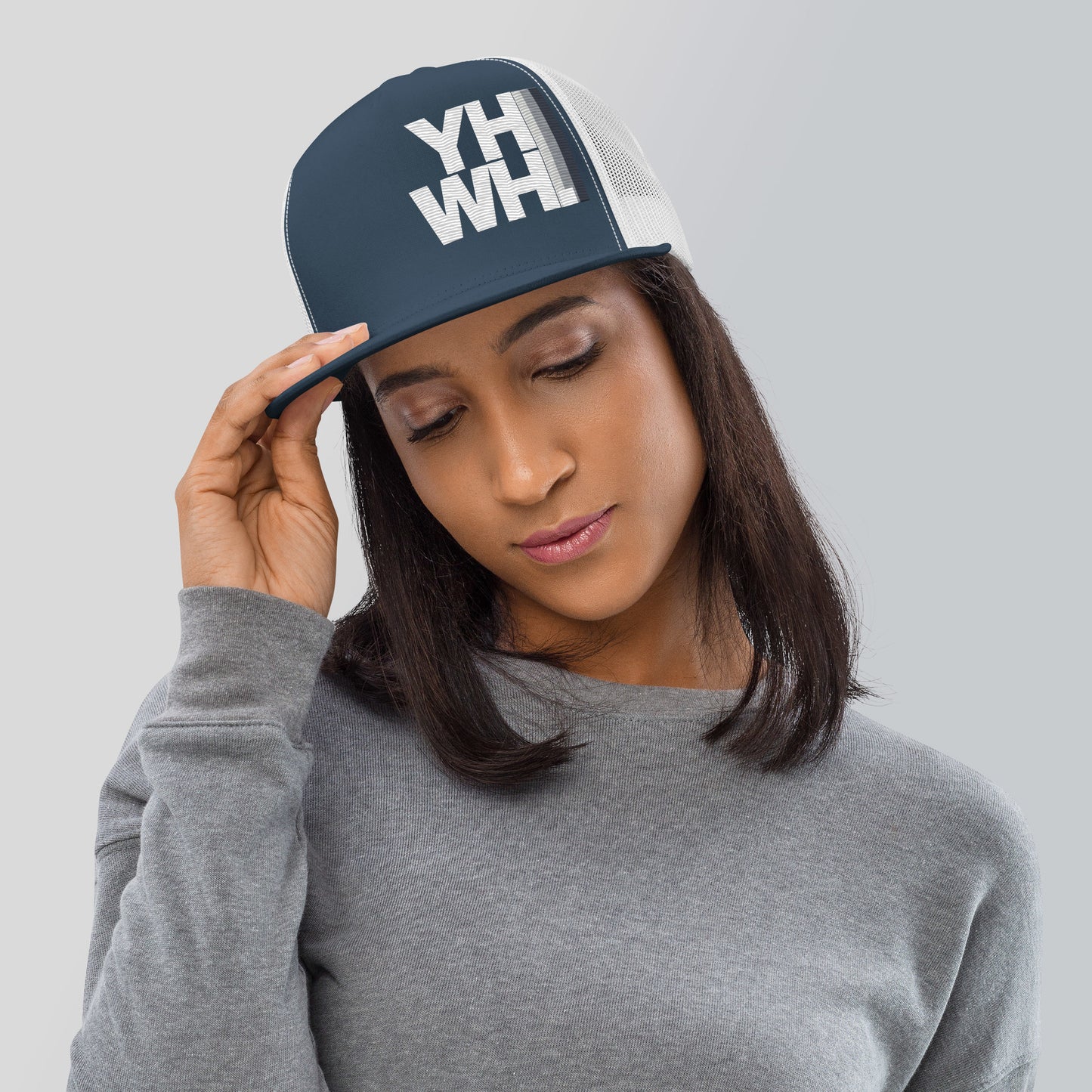 A woman wearing the YHWH Unisex Trucker Cap, showcasing a stylish embroidered design that conveys faith. This cap is perfect for expressing your beliefs with style, supporting a veteran-owned small business. Ideal for casual outings or workouts.