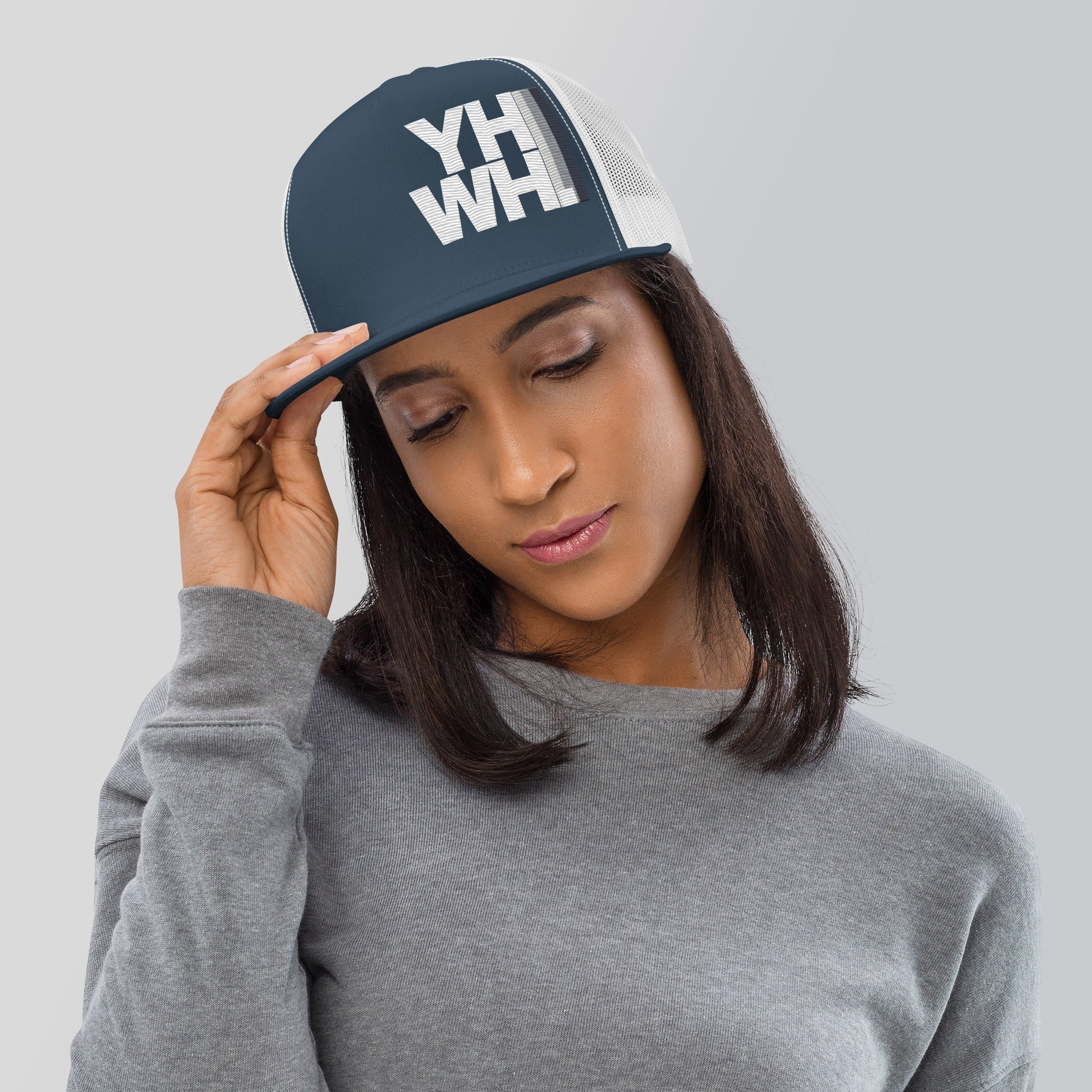A woman wearing the YHWH Unisex Trucker Cap, showcasing a stylish embroidered design that conveys faith. This cap is perfect for expressing your beliefs with style, supporting a veteran-owned small business. Ideal for casual outings or workouts.